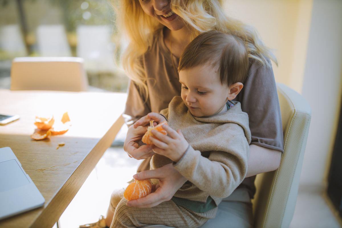 Enfant qui épluche une orange, un geste du quotidien qui apprend à la main à doser sa force
